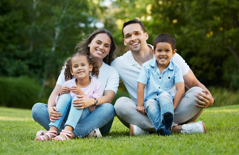 family sitting on green healthy lawn